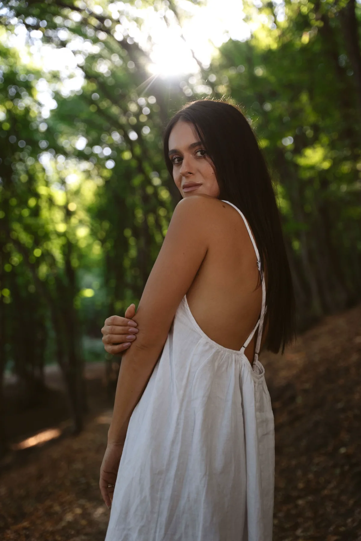 Femeie în rochie albă, în pădure, privind peste umăr